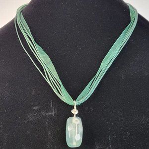 Green semi-precious stone pendant on green ribbon and cord necklace
